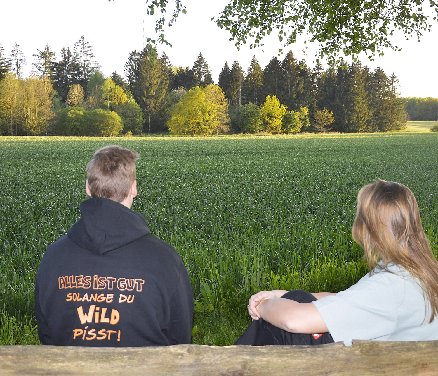 Auf einer Bank sitzt jemand mit dem Pfadi-Drip Hoodie "Wild"
